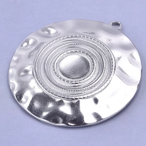 Macro detail of silver 304 stainless steel round pendant with concentric hammered texture
