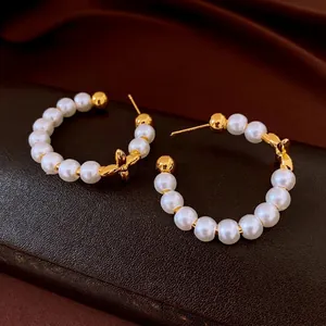 Elegant gold-plated C-shaped pearl hoop earrings featuring a dainty butterfly design