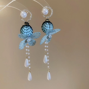 Close-up of floral drop earrings with blue lace petals, pearls and zircon details