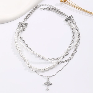 Detail view of a multi-layer necklace with silver chains, pearls and a cross pendant