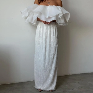 Elegante top bianco con volant scoperte e gonna lunga con paillettes e nappe per feste
