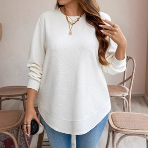 Close-up of white waffle knit texture and irregular curved hem on a casual long sleeve top