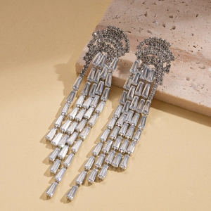 Macro detail of silver tassel earrings with zircon stones on a rustic stone background