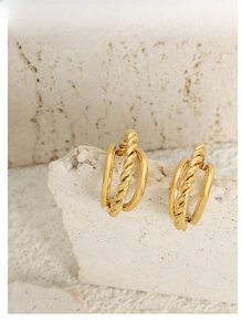 Macro detail of 18K gold plated C-shaped twisted rope earrings on a stone base