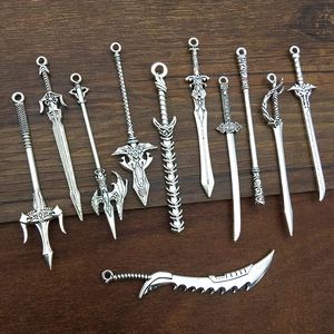 Macro shot of silver alloy sword pendants with fantasy weapon designs on wood background