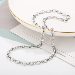 Detailed view of silver stainless steel pig nose chain necklace on a white ceramic plate