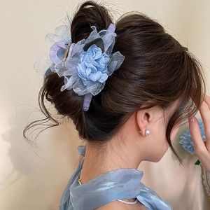 Detail showing a blue mesh rose hair claw clip worn by a model in a soft lighting scene
