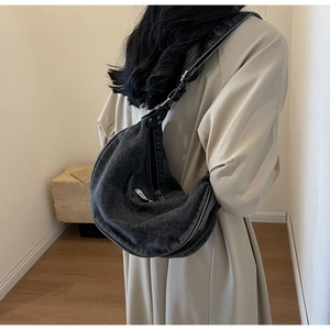 Model wearing a dark gray washed denim crescent crossbody bag with adjustable strap