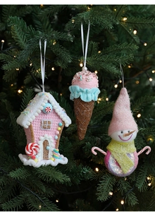 Close-up of pink gingerbread house and ice cream ornaments on a Christmas tree