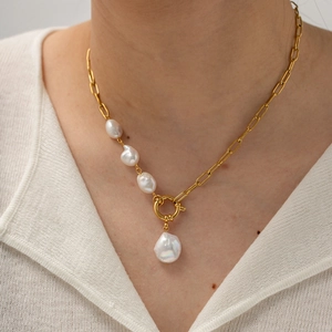Collar de perlas barrocas con cadena de clip dorada llevado por modelo en blanco