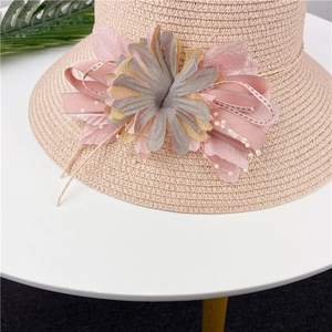Detail of pink straw hat with artisanal floral decoration, pearls and satin ribbon trim