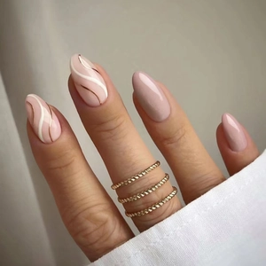 Almond press-on nails in nude pink with elegant white and gold swirl patterns and gold rings