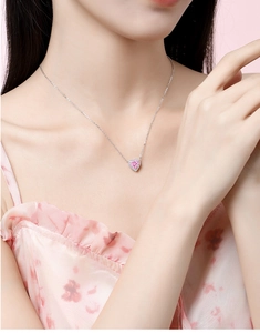 Close-up of heart necklace with pink gemstone pendant on model neck detail