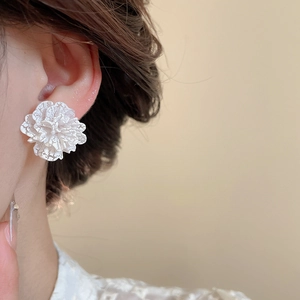 Dettaglio ravvicinato di orecchini a fiore bianco con perle e trama di pizzo