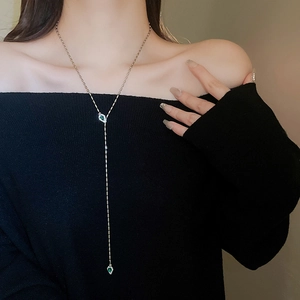 Detail of Y-shaped gold necklace with emerald water-drop pendants and pave diamonds