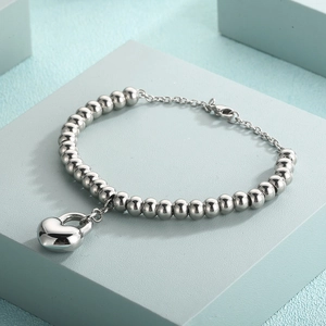 Polished silver heart padlock bead bracelet shown on a light green geometric podium stand