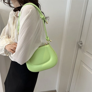 Vibrant green leather underarm bag for women with unique knot strap and saddle shape
