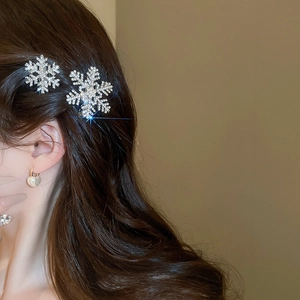 Close-up of sparkling snowflake hair clip with rhinestones worn on wavy brown hair
