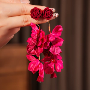 Gros plan sur des boucles d'oreilles fleurs en velours rouge aux pétales en tissu