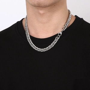 Close-up of silver stainless steel Cuban curb chain necklace worn by male model on neck