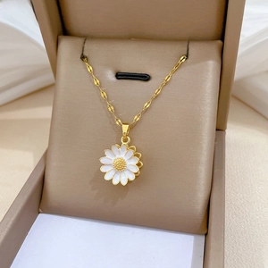 Close-up of a rotating sunflower pendant necklace with white enamel petals in a gift box