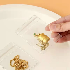 Close-up of a clear PVC jewelry bag with a golden necklace and lucky cat charm inside