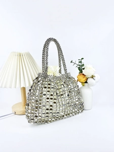 Detail of silver metallic sequin hollow hand-woven handbag with a cream inner drawstring bag