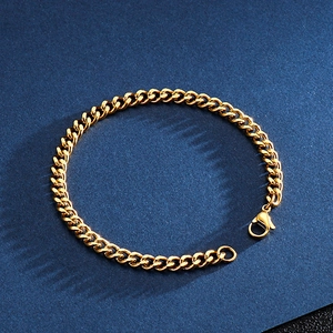 Detail of a golden cuban link bracelet with a lobster clasp on a dark blue surface