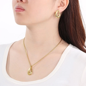 Elegant gold teardrop jewelry set with necklace and earrings worn on a model
