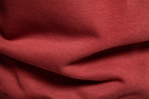 Close-up of red knitted cotton fabric texture with soft shadows for casual sweatshirt