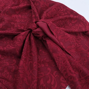 Dettaglio del tessuto in pizzo floreale rosso scuro con trama jacquard e design ritagliato