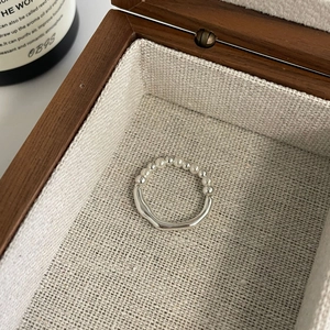 Macro shot of silver beaded ring with irregular lines on elegant wooden jewelry box