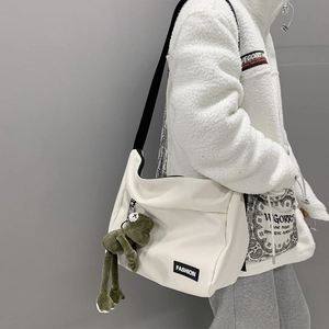 Japanese style white canvas messenger bag with a green frog pendant for street fashion