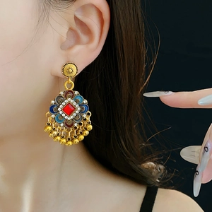 Détail de boucle d'oreille vintage fleur avec pierre rouge et émail bleu sur modèle
