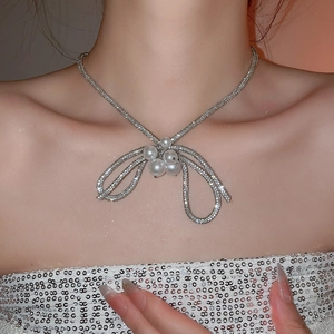 Close-up of elegant silver bow necklace with rhinestones and pearls worn by a model