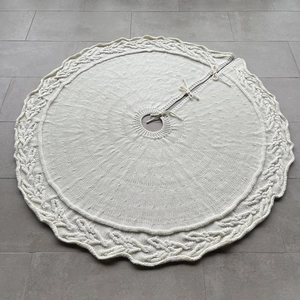 Detailed cable knit pattern and tie closures on a cream-white Christmas tree skirt