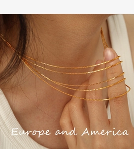 Detail of five-layer gold snake chain necklaces on model showing layered drape effect