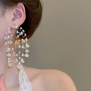 Close-up of model wearing colorful beaded hoop tassel earrings with vibrant sequins