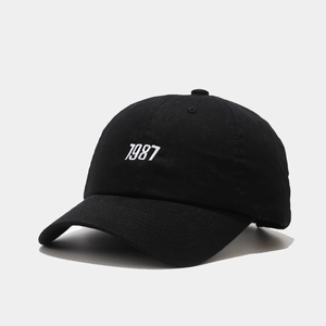 Detailed close-up of 1987 white embroidery on black cotton twill baseball cap