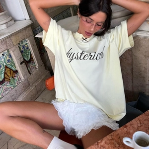 Dettaglio di t-shirt in cotone giallo chiaro con stampa hysteric e gonna di pizzo