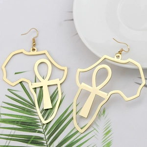 Détail de boucles d'oreilles carte d'Afrique dorées avec symbole Ankh sur marbre blanc