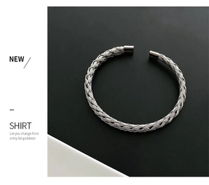 Close-up of silver-tone woven titanium steel cuff bracelet with intricate twisted design