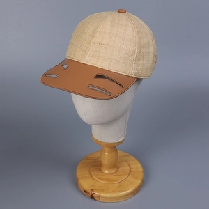 Close-up of raffia baseball cap featuring a leather brim with unique crescent cut-outs