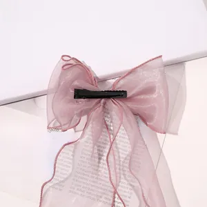 Detailed view of pink organza bow hair clip with sheer ribbons and metal duckbill clip