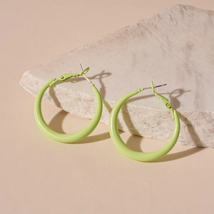 Detail of light green pastel hoop earrings on a textured stone display platform
