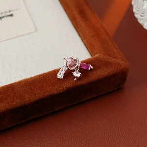 Macro detail of silver heart earrings with pink zircon stones on a brown velvet base