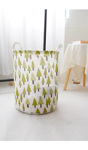 Detail of a foldable canvas laundry basket with green tree patterns and durable handles