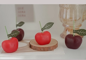 Detalle macro de velas con forma de cereza roja y púrpura con hojas verdes reales