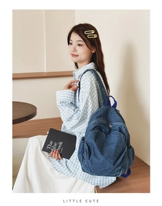 Detail of blue denim backpack with side pockets on female model in a cafe setting