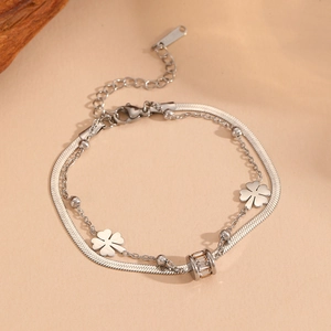 Detailed macro view of silver stainless steel double-layer clover bracelet on beige paper